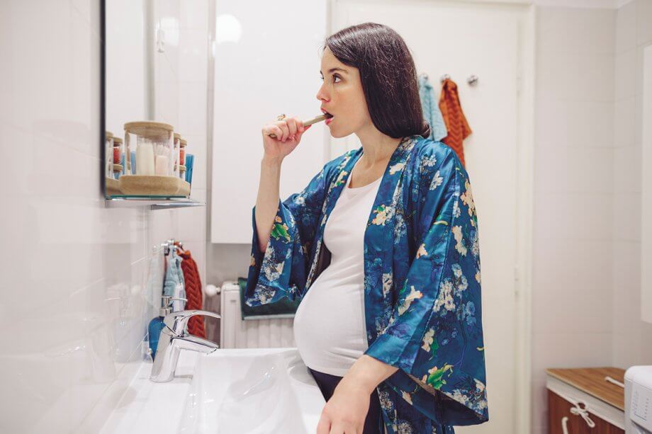 pregnant woman in bathrobe, brushing teeth